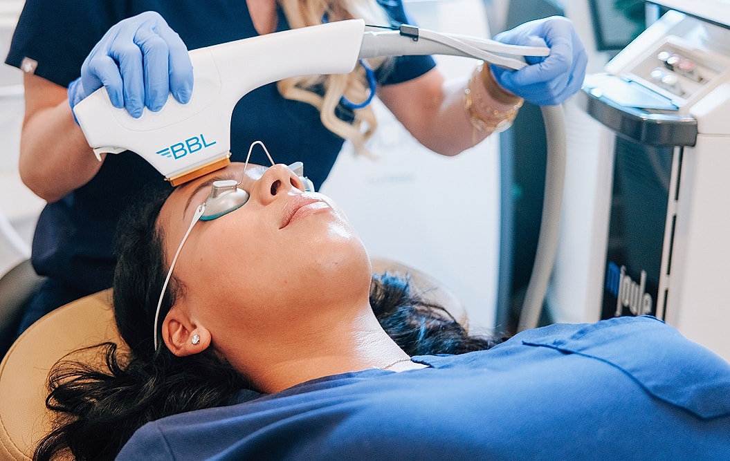 Woman receiving BBL facial treatment in clinic.
