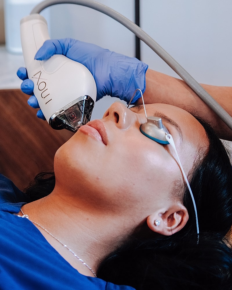 Facial treatment with laser device in progress.