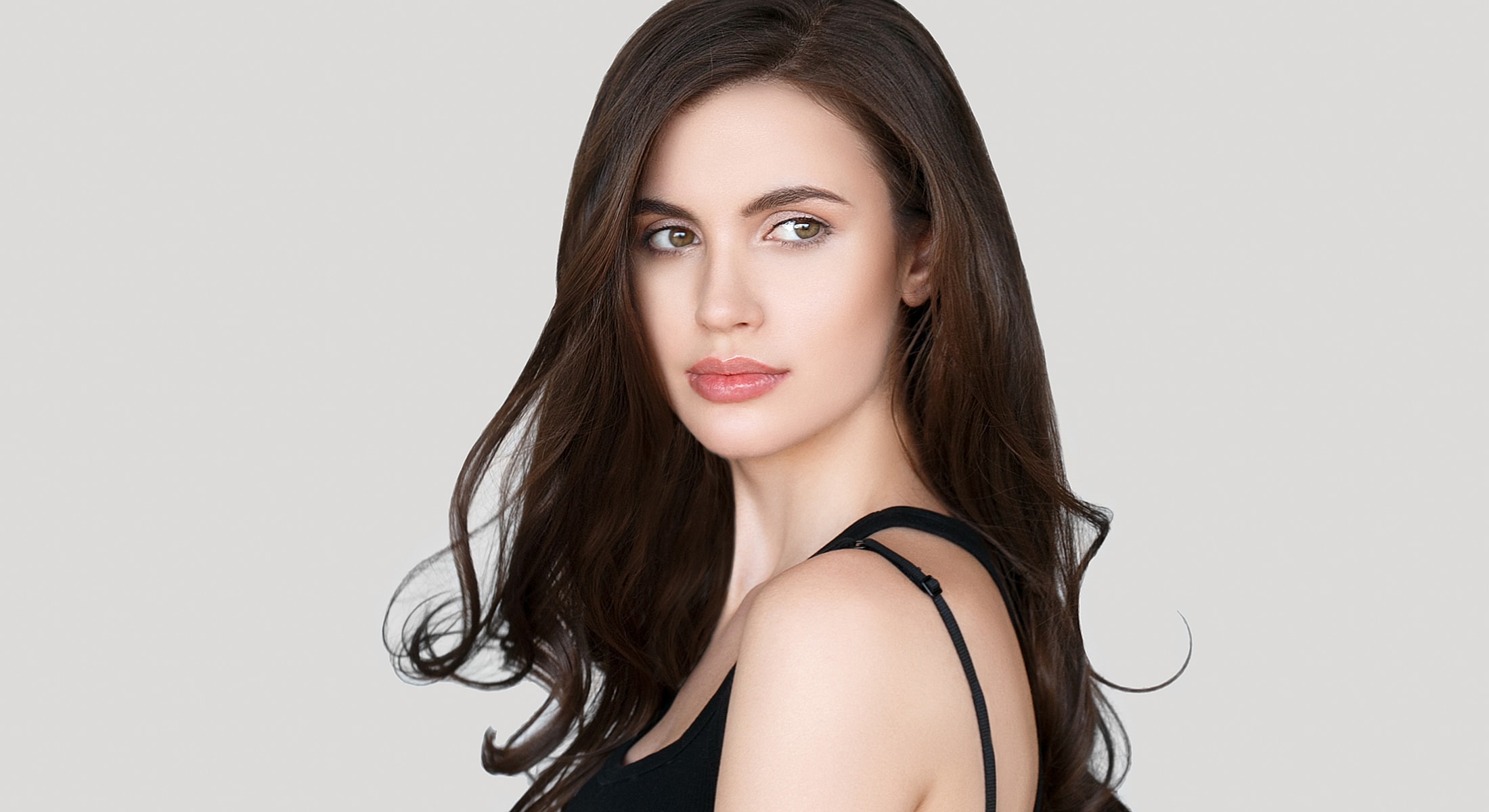 Woman with long hair against gray background.